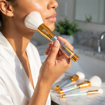 Person using a gleem brush on their face with additional brushes in the background.
